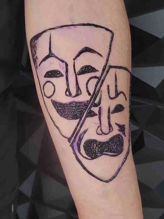 Minimal theatre mask line tattoo on forearm using jagua ink at Lethal Ink Tattoo Pattaya (2026)