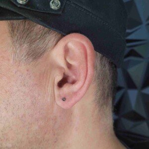 Ear lobe piercing with black cone stud on left ear at Lethal Ink Tattoo Pattaya. Ear lobe single ring piercing with black cone surgical steel stud on left ear at Lethal Ink Tattoo Pattaya (2026)
